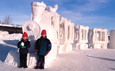 Two kids standing in front of snow sculpture - winter in Anchorage Alaska